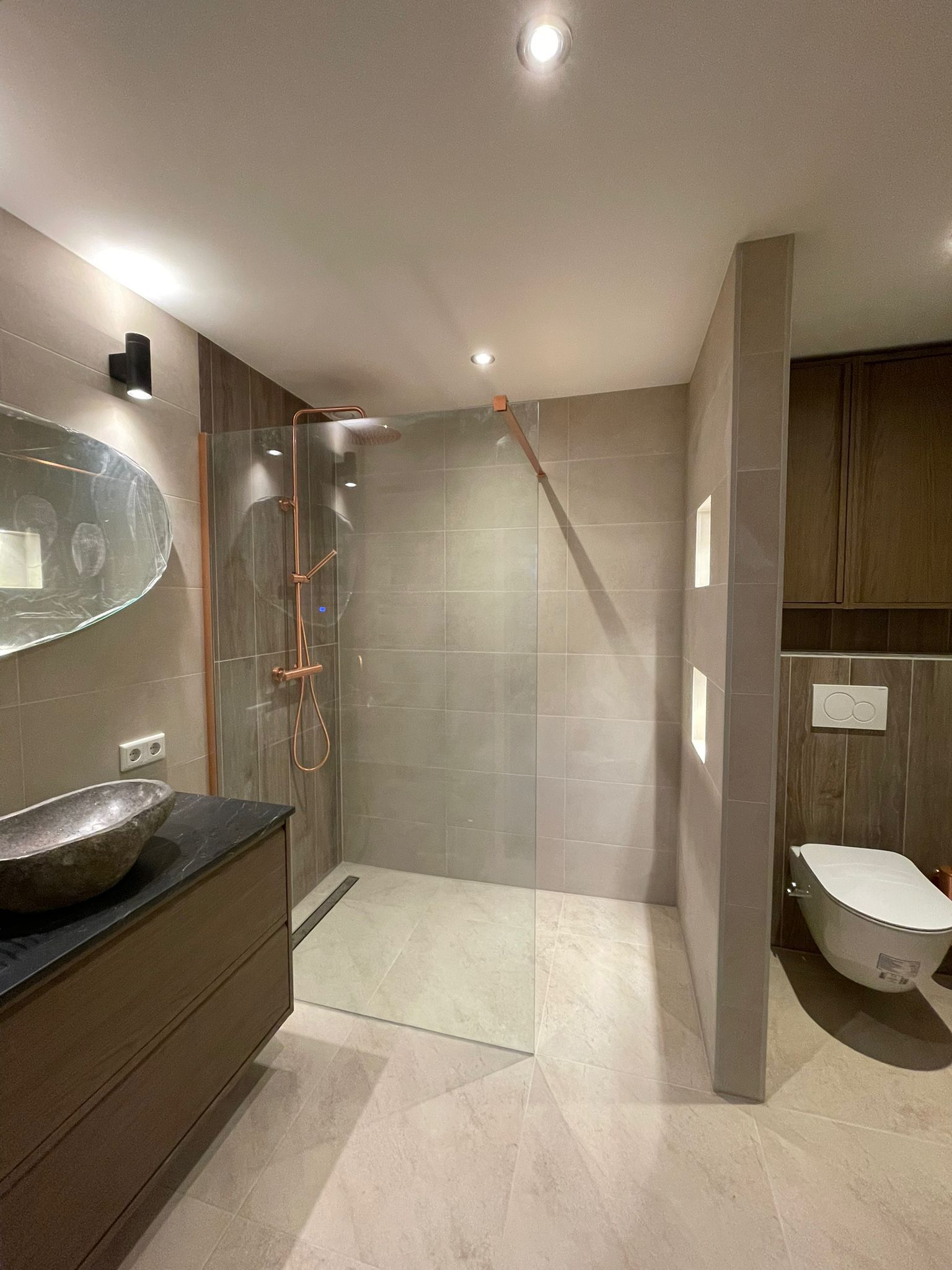 Detail badkamer renovatie Eindhoven, koperen regendouche, vanity met stenen wasbak en strakke afwerking